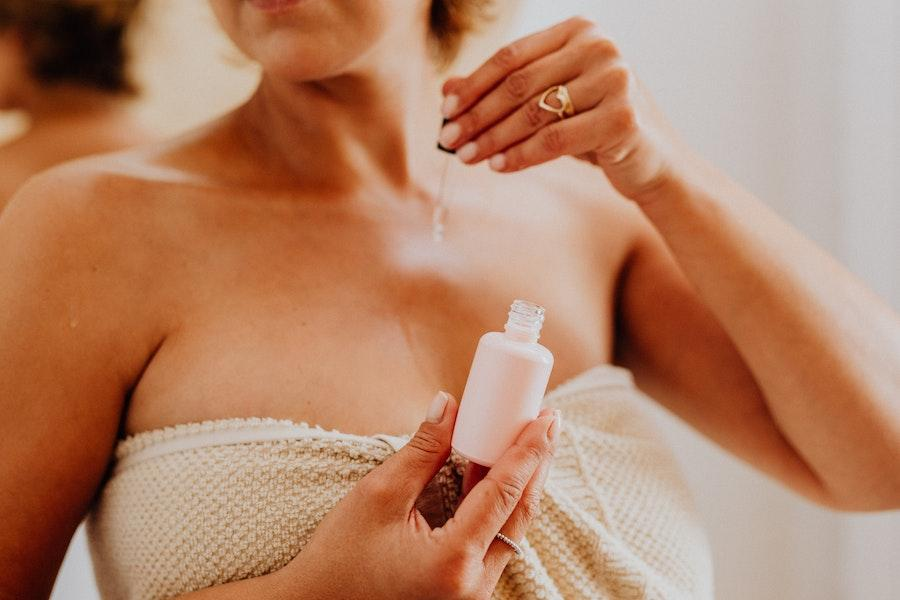 Woman applying body oil on her chest