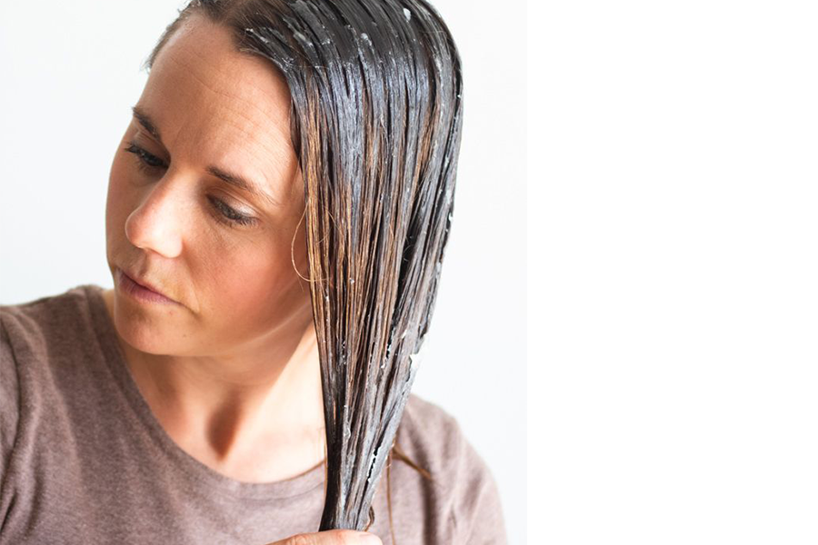 Woman applying hair mask on her brown hair