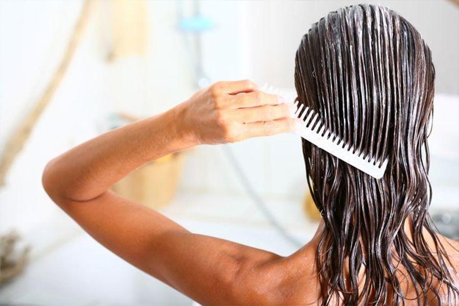 Woman combing her hair after applying hair mask