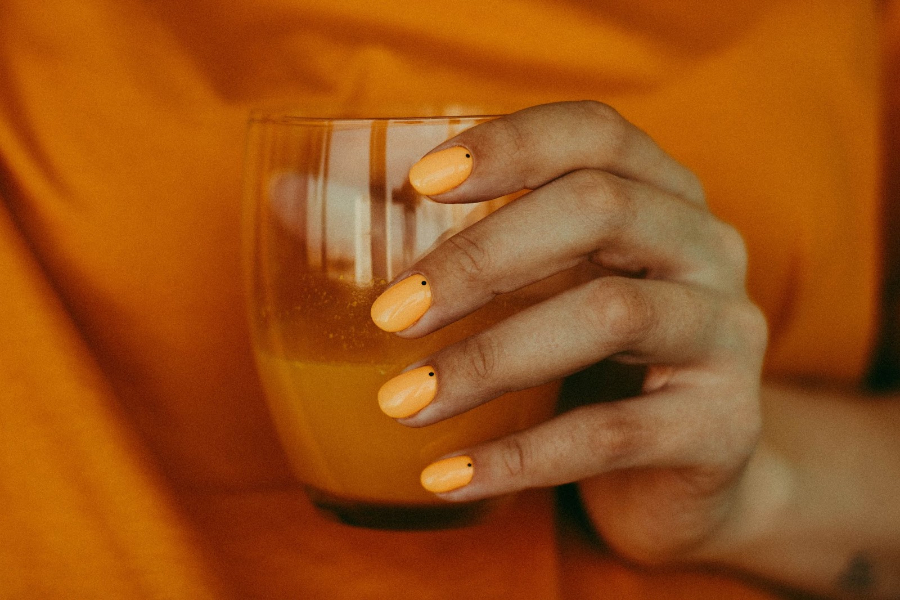 Woman holding glass and showing neutral nails