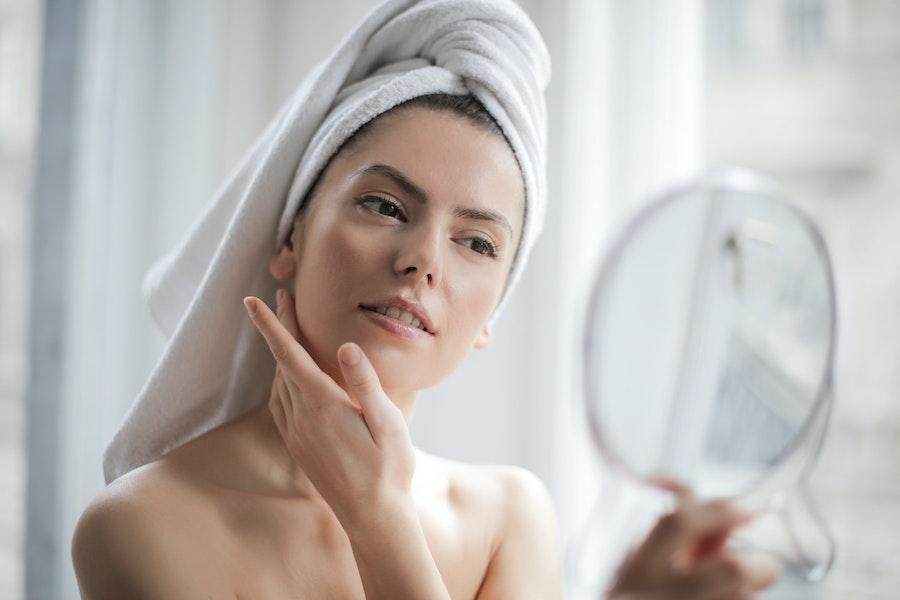 Woman performing beauty routine in front of a mirror