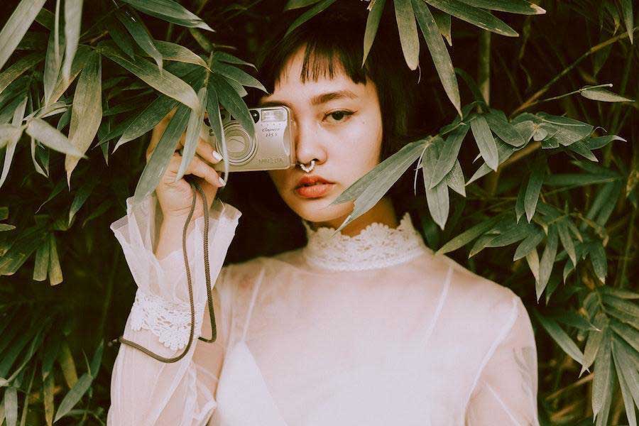 Woman posing with a camera while rocking a white dress