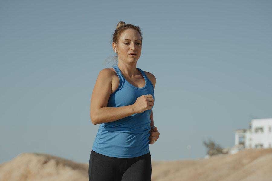 Woman running in a blue tank top and black leggings