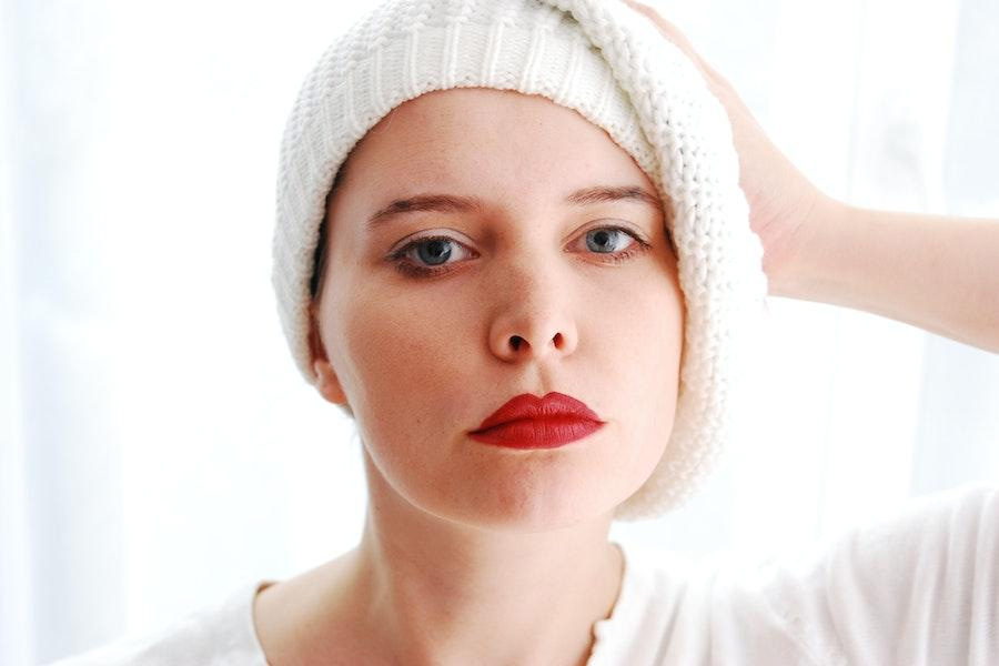 Woman styling a white beanie to one side
