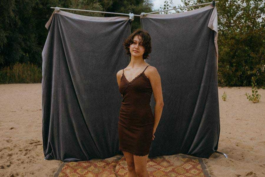 Woman wearing a brown dress posing with hands at her back