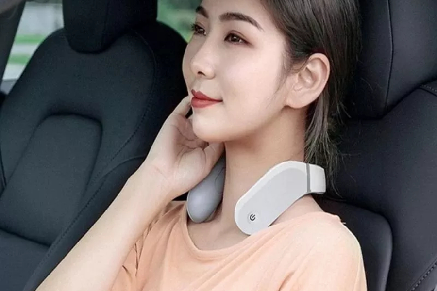 Woman wearing a neck massager while sitting in a car