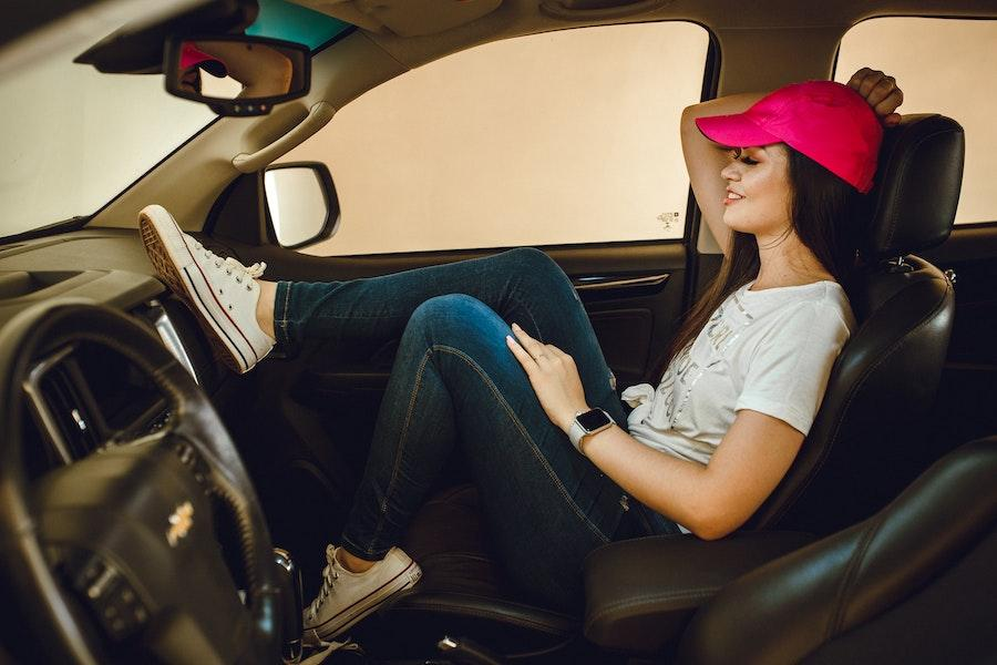 Woman wearing a pink baseball hat relaxing in a car
