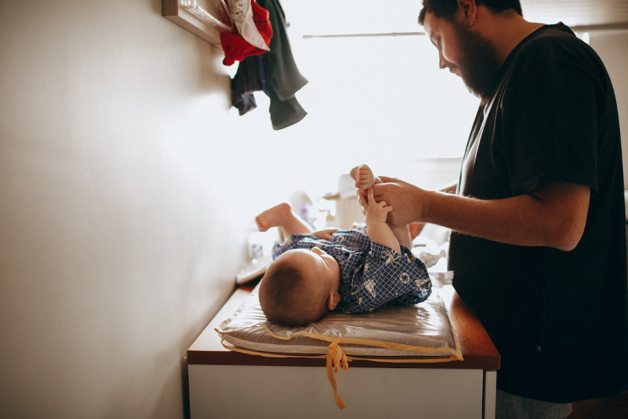 Young father changing the diaper of newborn baby