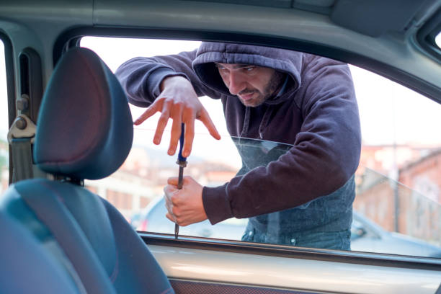 A thief breaking into the car through an open window