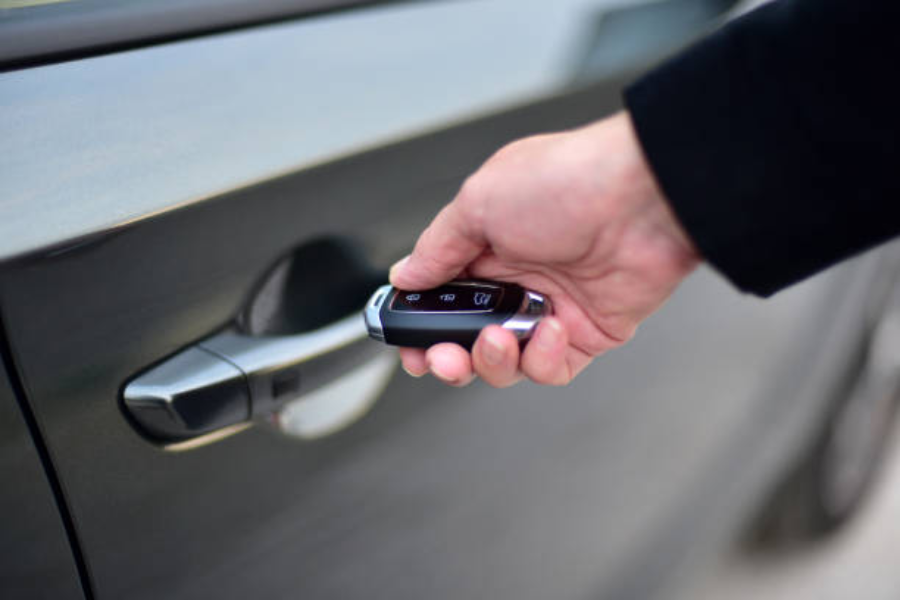 Remote controlled car key in hand next to car handle