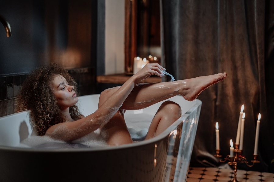 Woman shaving her legs in a bathtub