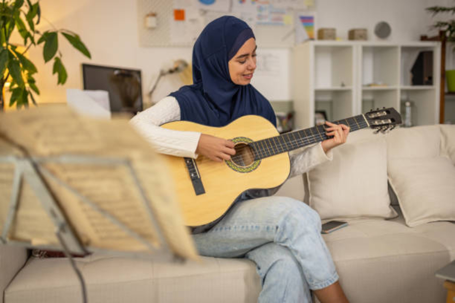 Woman sitting on couch playing an acoustic guitar