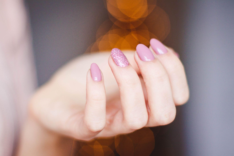 Woman with pink fingernails and one textured glitter accent nail